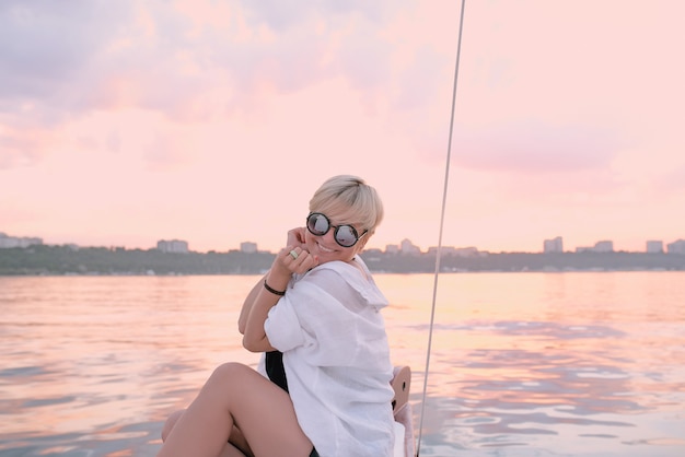 glückliche Frau, die den Sonnenuntergang auf der Yacht im Meer genießt