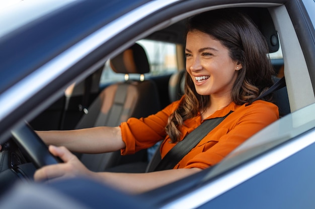 Glückliche Frau, die ein Auto fährt und lächelt. Nette junge Erfolgsfrau, glückliche brünette Frau fährt ein Auto. Porträt einer glücklichen Fahrerin, die ein Auto mit Sicherheitsgurt steuert