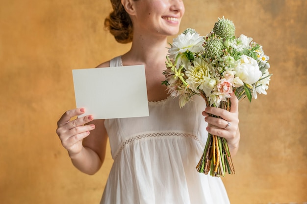 Glückliche Frau, die eine leere Karte mit einem Blumenstrauß hält