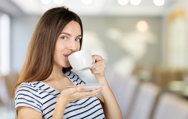 Glückliche Frau, die eine warme Tasse Tee oder Kaffee zum Frühstück genießt