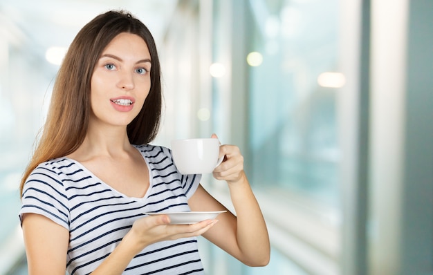 Glückliche Frau, die eine warme Tasse Tee oder Kaffee zum Frühstück genießt