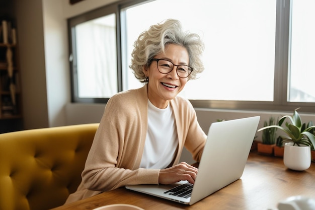 Glückliche Frau, die fernab vom Heimbüro arbeitet und sich mit dem Laptop Notizen macht. Geschäftsfrau mittleren Alters in den Sechzigern lächelt am Computer und schaut sich ein Webinar an