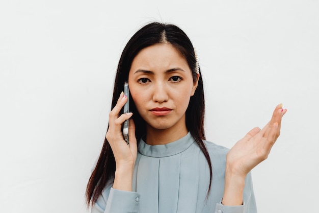 Glückliche Frau, die Handy gegen weißen Hintergrund beantwortet