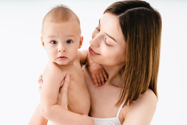Glückliche Frau, die ihr Baby auf farbigem Hintergrund hält - Junge Frau, die Unterwäsche trägt und sich um ihren kleinen Sohn kümmert - Schwangerschaft, Mutterschaft, Menschen und Erwartungskonzept