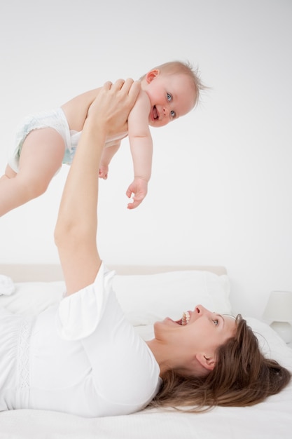 Glückliche Frau, die ihr Baby beim Lügen hält