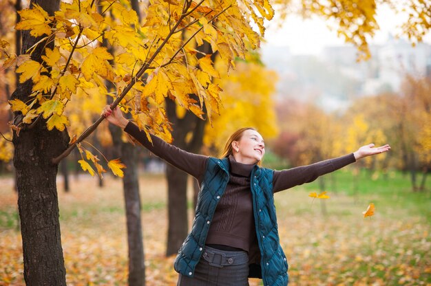 Glückliche Frau, die im Herbstpark lächelt und tanzt.