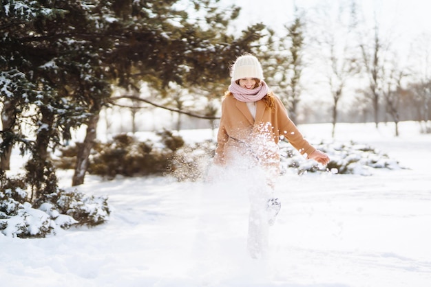 Glückliche Frau, die in den verschneiten Wintertag im Freien geht Wintermodeferien ruhen Reisekonzept