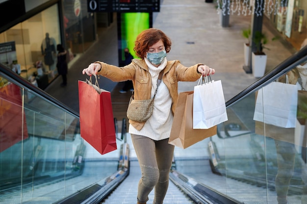 Glückliche Frau, die in einem Einkaufszentrum mit Gesichtsmaske einkauft, neue normale, covid-19