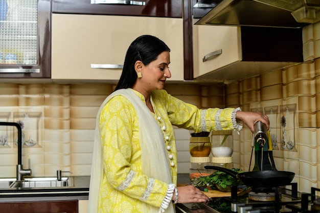 glückliche Frau, die in ihrer Küche indisches pakistanisches Modell kocht