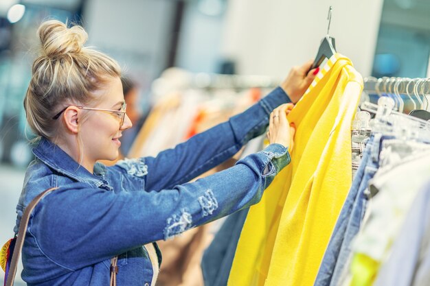 glückliche Frau, die Kleidung im Geschäft kauft