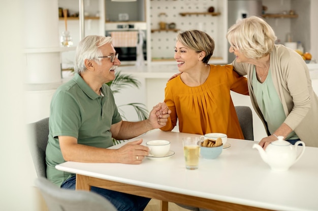 Glückliche Frau, die mit ihren älteren Eltern spricht, während sie sie zu Hause besucht