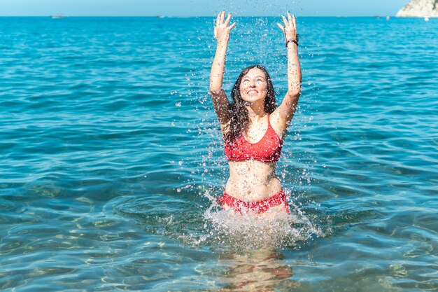 Glückliche Frau, die mit Wasser spielt