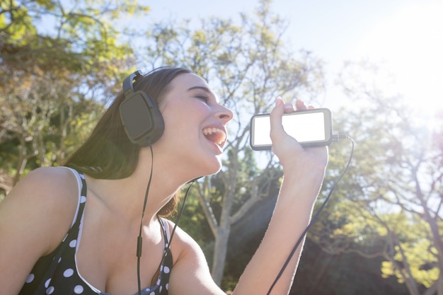 Glückliche Frau, die Musik auf Handy hört