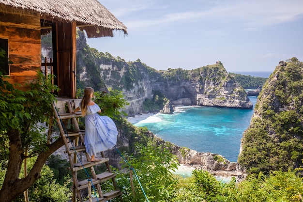 Foto glückliche frau, die nahes baumhaus am standpunkt tausend insel nusa penida steht