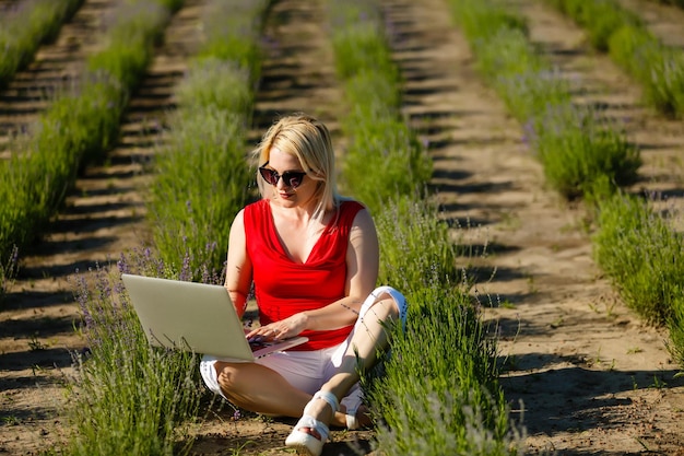 Glückliche Frau, die online Urlaub plant und Informationen auf einem Laptop in einem Resort oder Hotel am Strand sucht