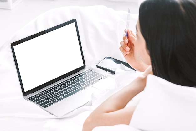 Glückliche Frau, die sich zu Hause digitale Laptop-Computer auf dem Bett entspannt und verwendet