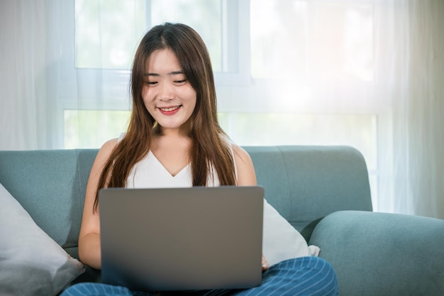 Glückliche Frau, die während der Freizeit auf einem Laptop-Computer im Internet surft