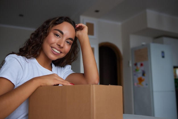 Glückliche Frau, die zu Hause Behälter auspackt und Karton öffnet, der in das Paket schaut Lächelnder zufriedener Kunde, der ein Paket vom Bestelllieferdienst erhält, der den Kauf auspackt