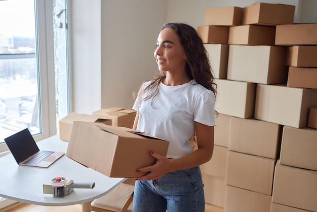 Glückliche Frau, die zu Hause Behälter auspackt und Karton öffnet, der in das Paket schaut Lächelnder zufriedener Kunde, der ein Paket vom Bestelllieferdienst erhält, der den Kauf auspackt