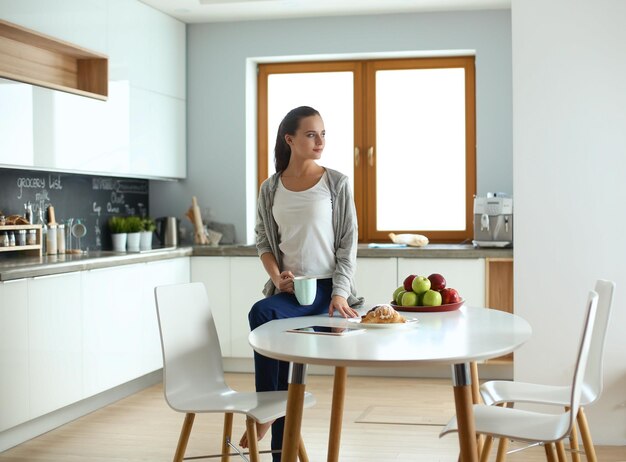 Glückliche Frau, die zu Hause Tee in der Küche trinkt