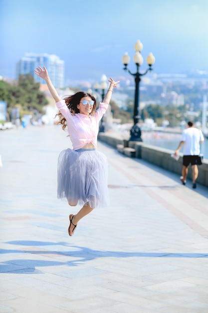 Glückliche Frau durch Tanzen über das Meer in einem gewundenen Kleid