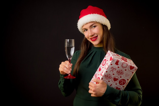 Glückliche Frau im grünen Kleid mit Champagner und Weihnachtsgeschenk