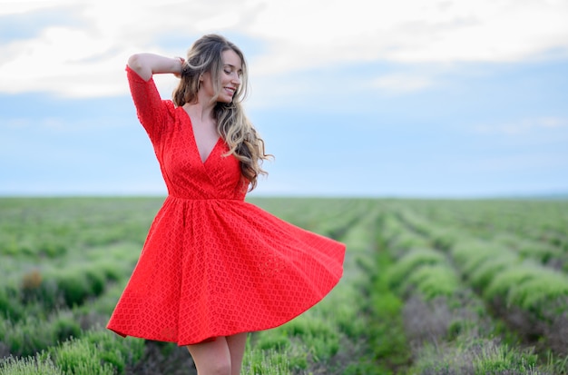 Glückliche Frau im roten Kleid, die im Lavendelfeld tanzt und springt