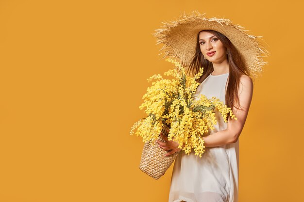 Glückliche Frau im Sommer weißes Kleid Strohhut mit Blumenstrauß in der Tasche