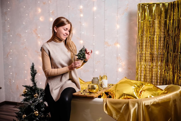 Glückliche Frau im Zimmer des neuen Jahres Neujahrsdekoration des Zimmers in goldener Farbe Das Konzept der Ferien- und festlichen Gestaltung Wohnkultur für das neue Jahr