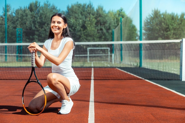 Glückliche Frau in Sportkleidung mit Tennisschläger