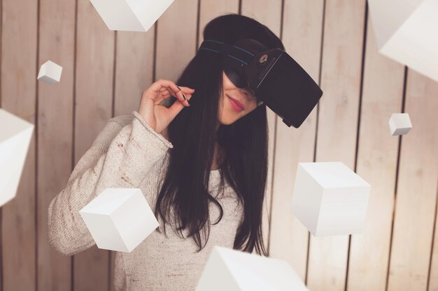 Glückliche Frau in VR-Brille mit 3D-Objekten herum
