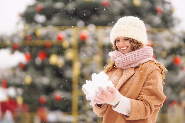 Glückliche Frau in Winterkleidung vor dem Hintergrund von Girlandenlichtern Wintermodeurlaub