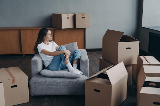 Glückliche Frau ist ein Wohnungskäufer Mover träumt zwischen Kisten im Wohnzimmer eines neuen Zuhauses