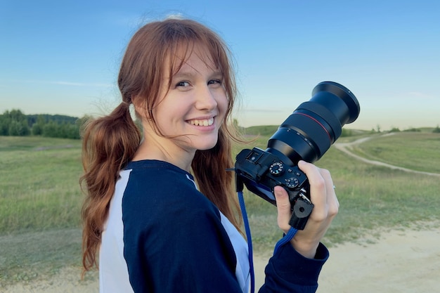 Glückliche Frau ist eine professionelle Fotografin mit DSLR-Kamera im Freien und Sonnenlichtporträt