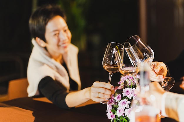 Glückliche Frau klirrt mit einem Glas Wein, während die Familie am Esstisch sitzt