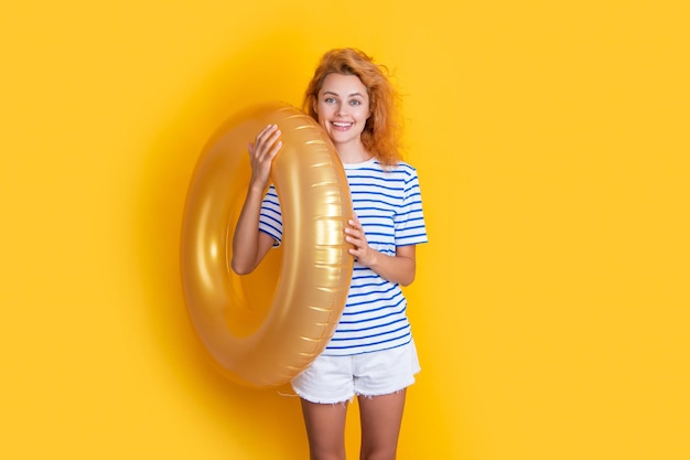 Glückliche Frau mit aufblasbarem Ring isoliert auf gelbem Hintergrund Sommerferien