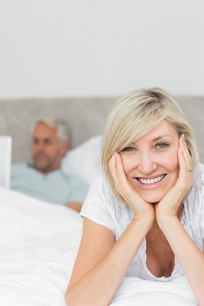 Glückliche Frau mit dem Mann, der Laptop im Bett verwendet