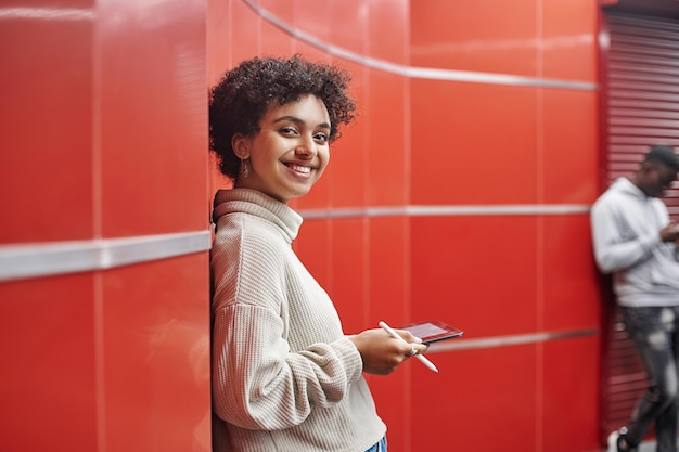 Glückliche Frau mit einem digitalen Tablet, das in der U-Bahn steht