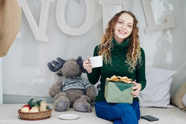 Glückliche Frau mit Geschenk und Teetasse