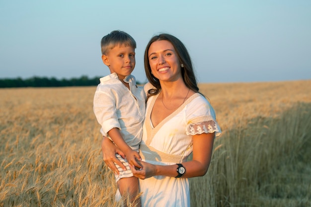 Glückliche Frau mit ihrem schönen Sohn auf einem Weizengebiet. Liebe und Mutterschaft