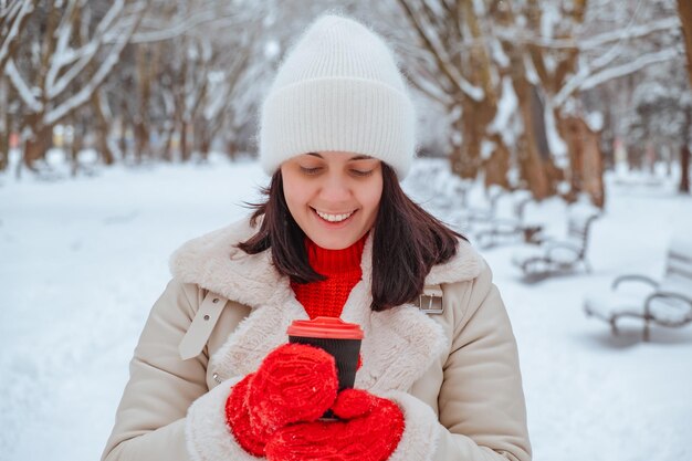 glückliche Frau mit Kaffeebecher im Freien an einem kalten Wintertag