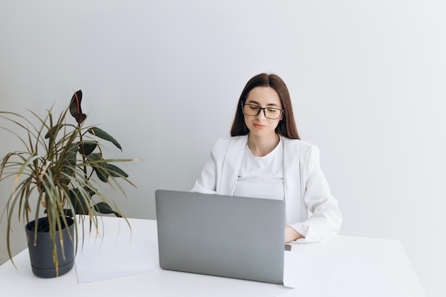 Glückliche Frau mit Laptop am modernen Arbeitsplatz