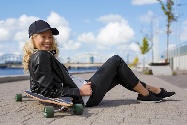 Glückliche Frau mit Longboard auf dem Boden sitzend