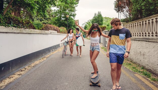 Glückliche Frau mit Sonnenbrille und Sommerkleidung, die an einem sonnigen Tag mit ihren Freunden auf Skate reitet. Junges Lifestyle-Konzept.