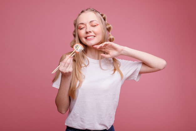 Glückliche Frau mit Sushi auf einer rosa Oberfläche