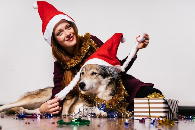 Glückliche Frau mit Weihnachtsmütze sitzt neben einem Hund