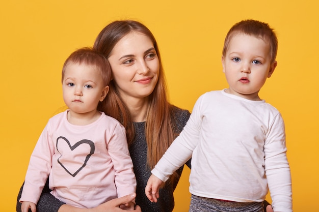 Glückliche Frau, Mutter und ihre Zwillingskleinkinder posieren im Fotostudio