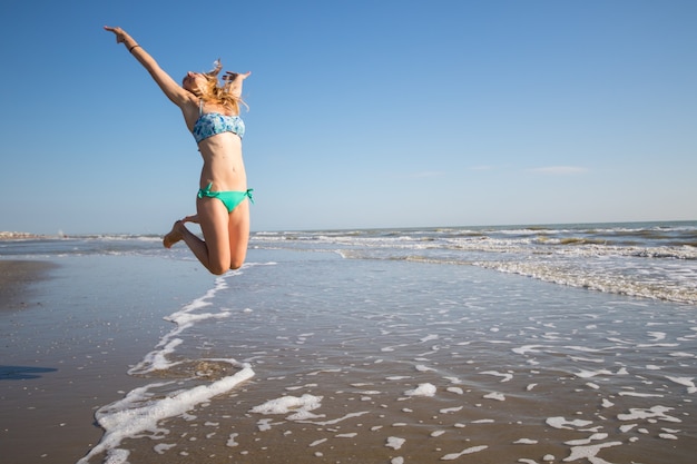 Glückliche Frau spielt am Strand