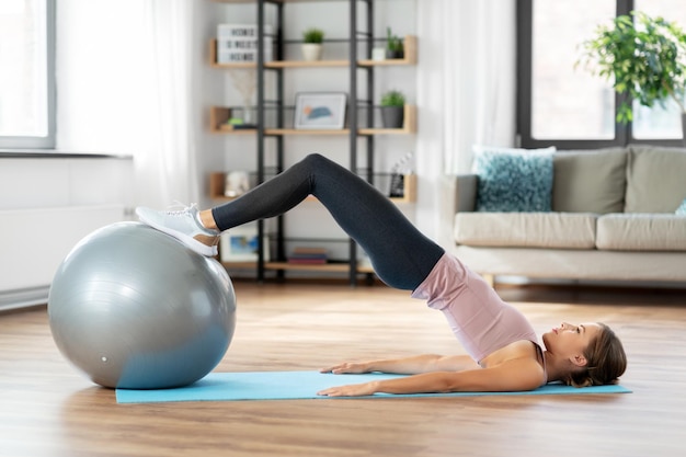 glückliche Frau trainiert zu Hause mit einem Fitnessball