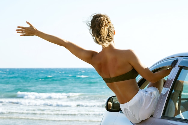 Glückliche Frau und Auto am Strand